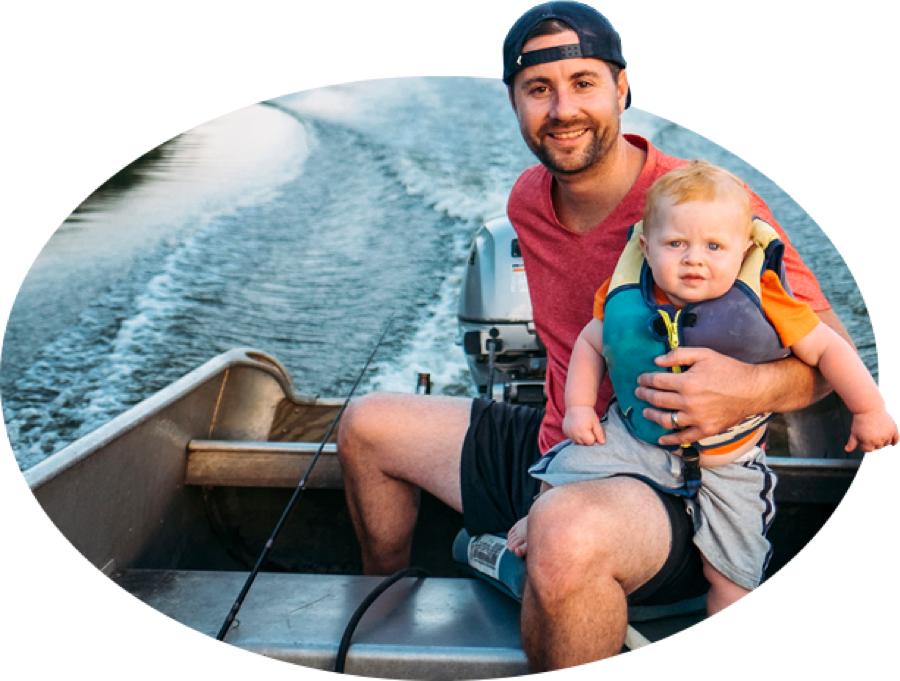 一位留着胡子的年轻父亲和他穿着救生衣的蹒跚学步的孩子乘着一艘渔船在水面上滑行, 州立农场船舶pp王者电子官网承保的多种类型之一.